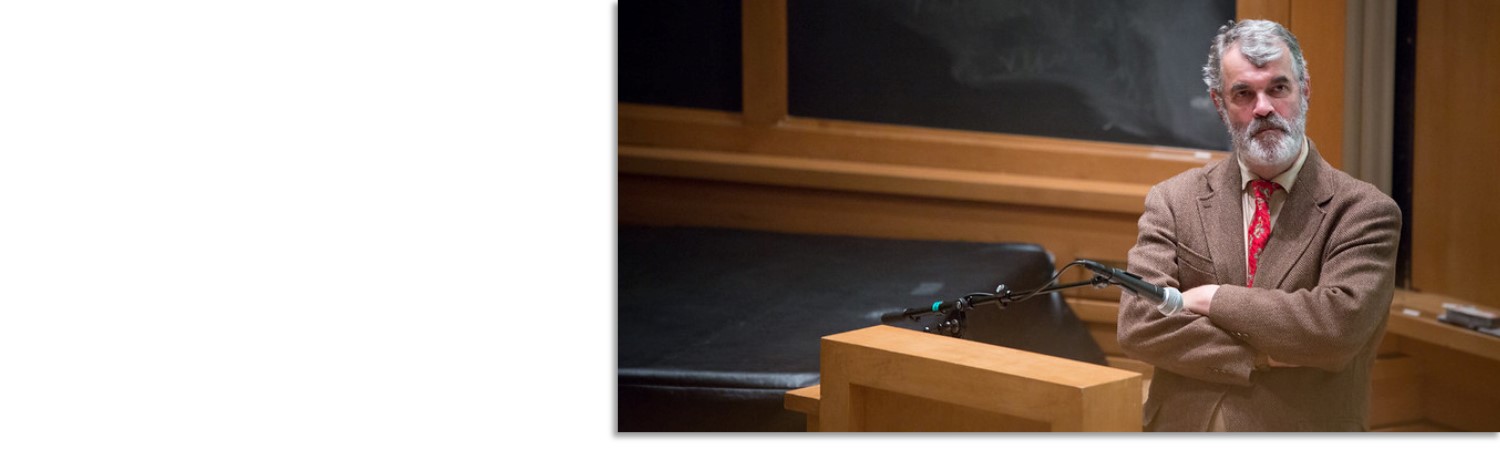 Graham Hodges Standing on a stage alone addressing a crowd of students 