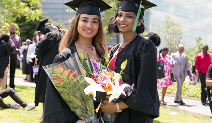 Two graduates holding flowers