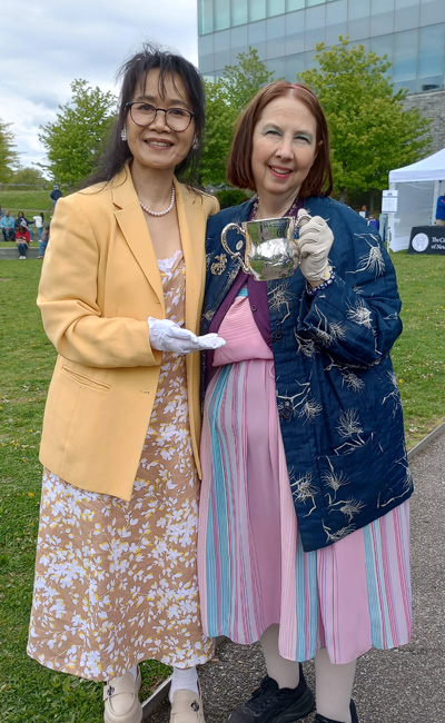  Linda Li (Class of 2025), left, and CCNY archivist Sydney Van Nort (Class of 2004 M.A.) with the Loving Cup.