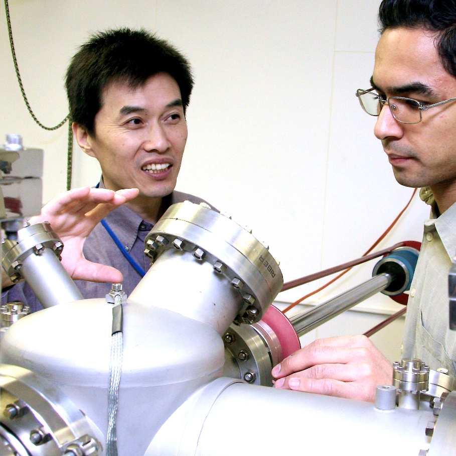 Professor Aidong Shen, left, and graduate student prepare to use molecular beam epitaxy chamber.