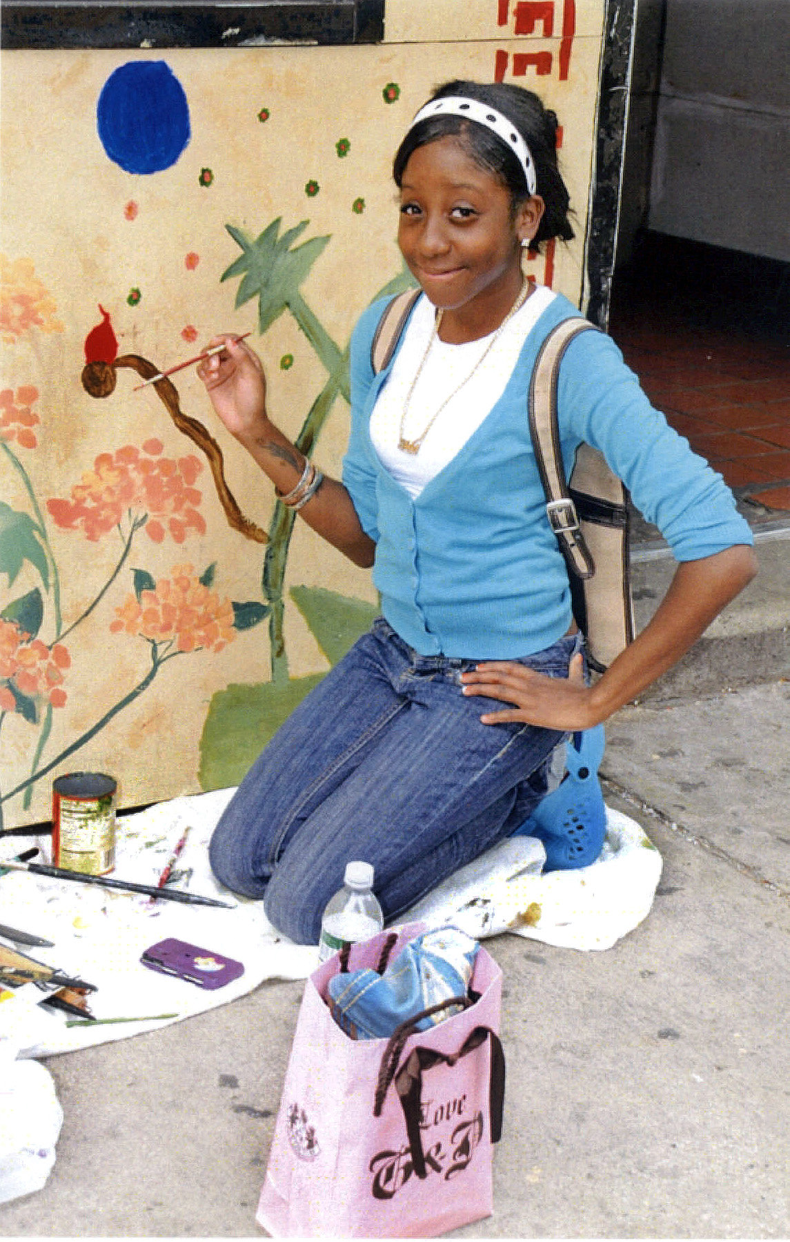 Ivory Tiffany Johnson working on a mural on the facade of the Luck Joy restaurant in Central Harlem.