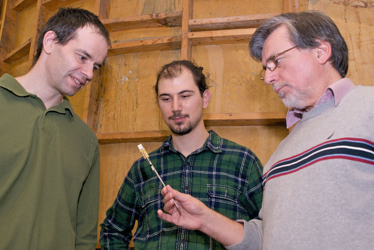 Professor Niell Elvin (left), graduate student Dogus Akaydin and Professor Yiannis Andreopoulos discuss properties of a piezoelectric strip (in Professor Andreopoulos' hand) that generates electricity when an air flow passes over it.