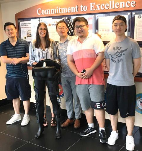 CCNY Mechanical Engineering Professor Hao Su [third from left] with members of his research team and a model of their exoskeleton.