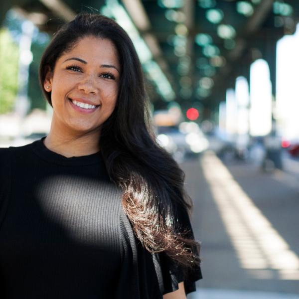 sarai perez woman standing outside under overhead train tracks in new york city