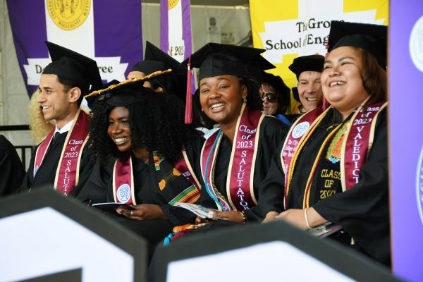 Salutatorian Kethia Calixte-Sanon Smiling at the Camera while Sitting in Full Regalia at Commencement Stage