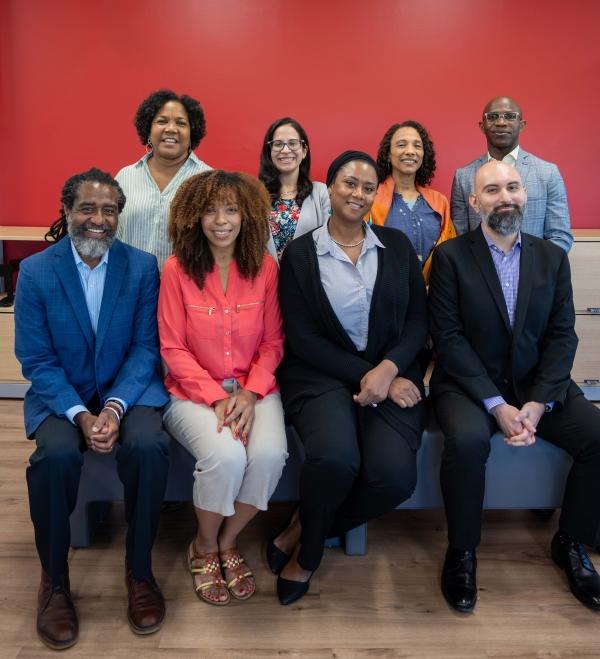 8 Colin Powell School Academic Advisors sitting in and smiling for a group photo.