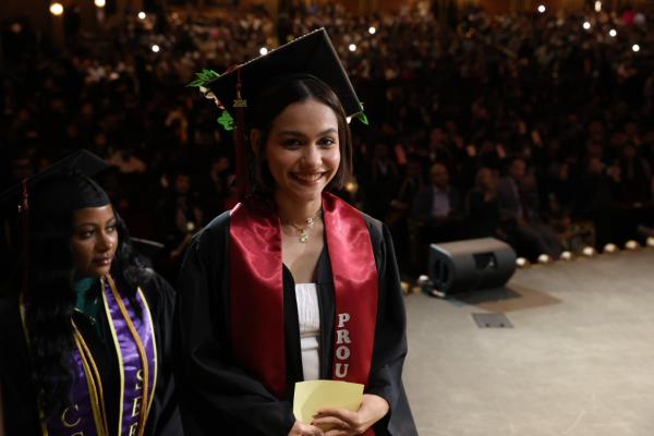 Colin Powell School Student walking up stage and smiling at the camera