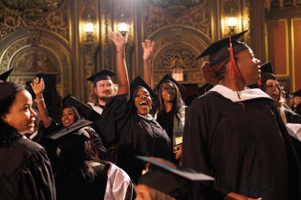 Group of Graduate Students smile and wave to their guests at the United Palace Theater