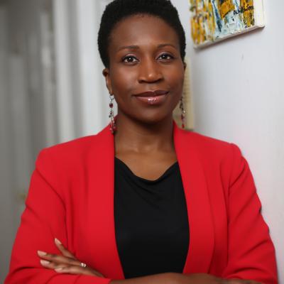 Dr. Onyinye Balogun in a red blazer, smiling and looking straight at the camera with arms crossed.