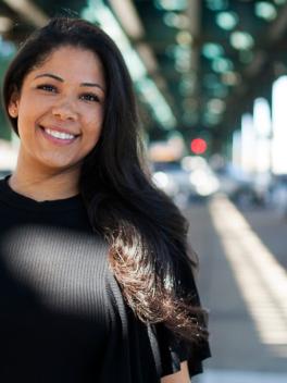 sarai perez woman standing outside under overhead train tracks in new york city