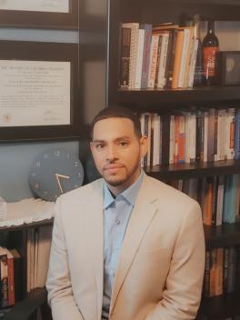 Dr. Thompson sitting in front of o book shelf